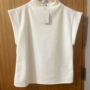 Mock high neck sleeveless top in a off white color
